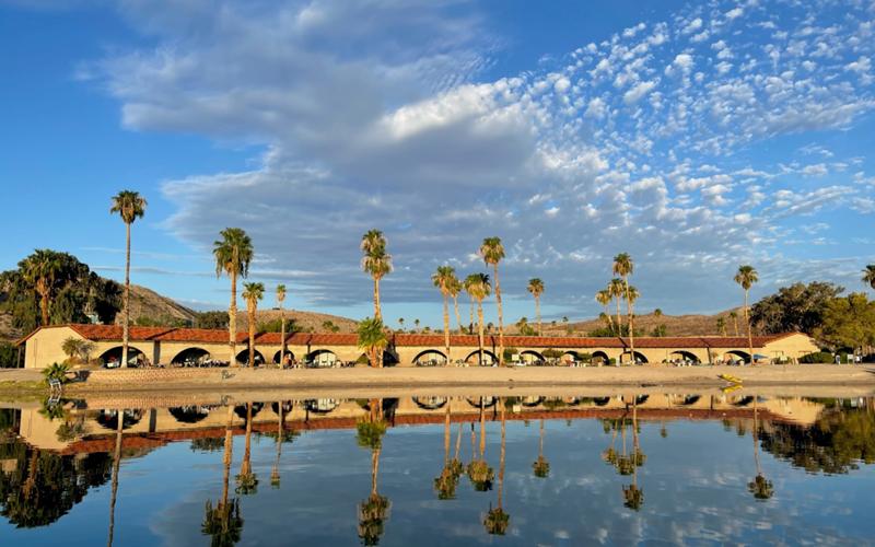 Single story motel exterior with room doors and parking, lit by warm golden hour desert light