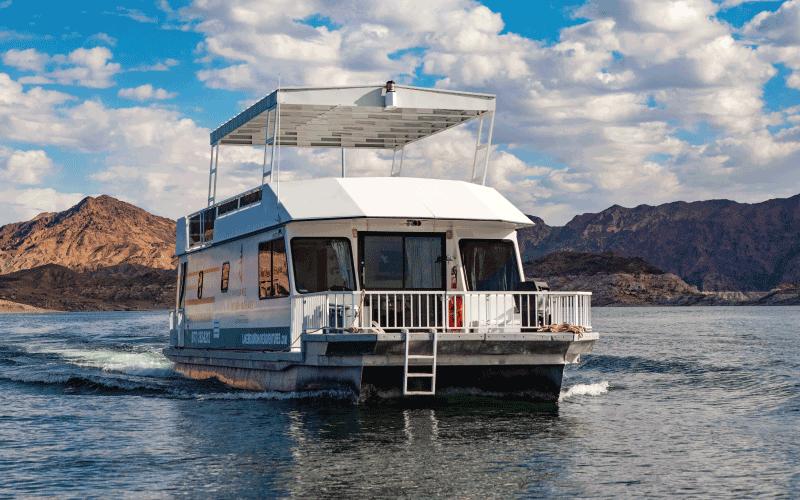 Two room houseboat cruising on Lake Mohave with desert mountains behind it