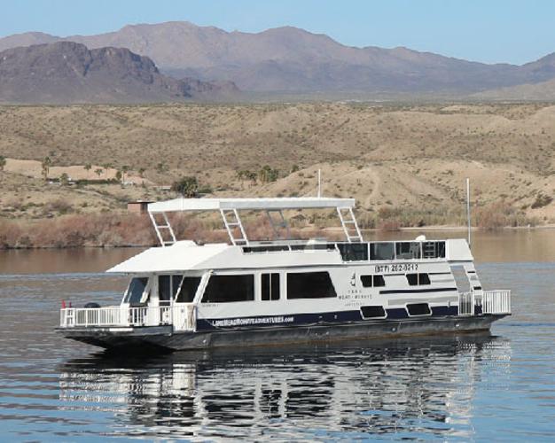 Four room houseboat with upper sundeck on calm lake water near desert hills