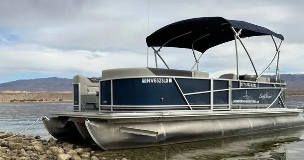 Pontoon patio boat tied up along the rocky shoreline at Cottonwood Cove on Lake Mohave